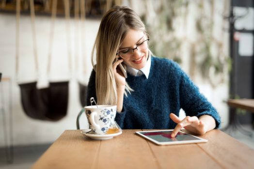 Young woman talking on phone and using tablet